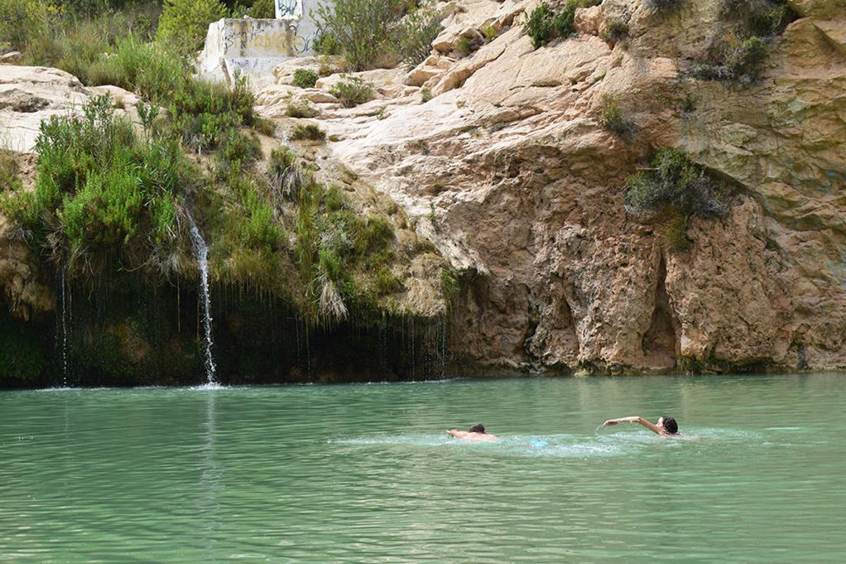 Dos bañistas nadan en Fuente Caputa, Mula.