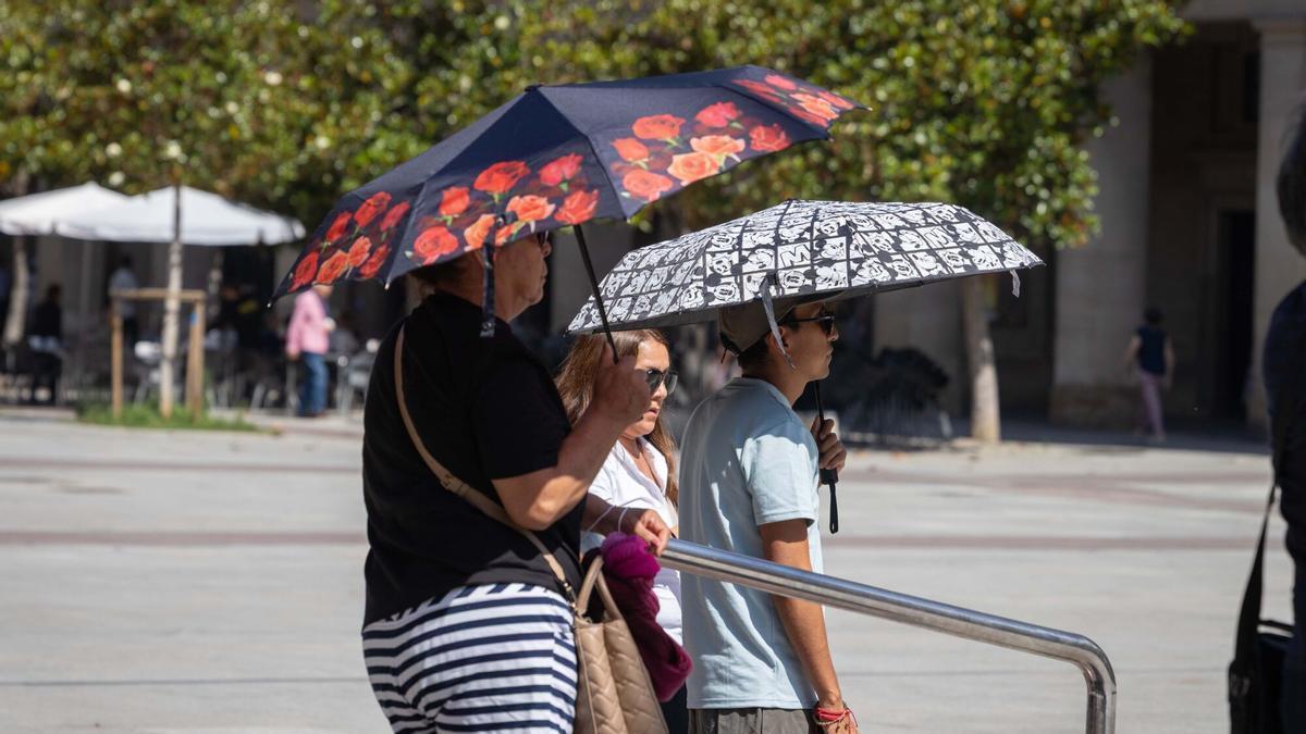 Varias mujeres se protegen del sol con paraguas en la plaza del Pilar de Zaragoza