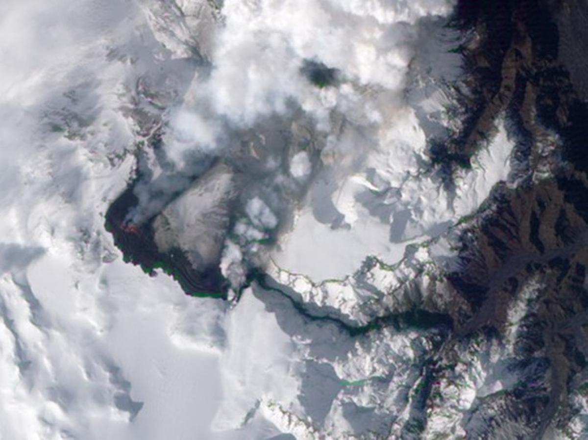 The ice-covered summit of Icelands Eyjafjallajokull volcano can be seen with fluïu magma erupting and a lava flow spreading northeast, spilling into Hrunagil Gully