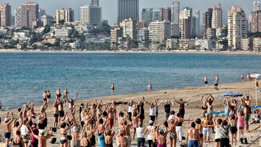 Turistas jubilados haciendo gimnasia en la playa de Levante (Benidorm).