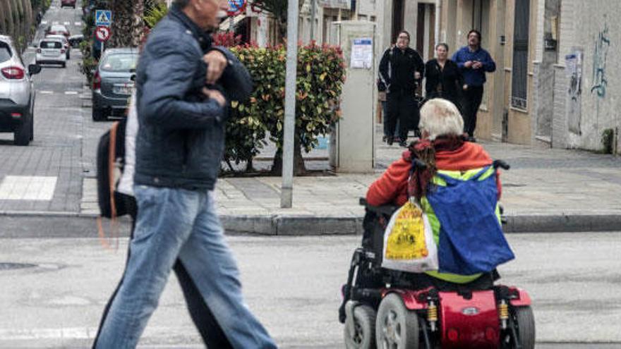 Una silla de ruedas a motor circula por una calle.