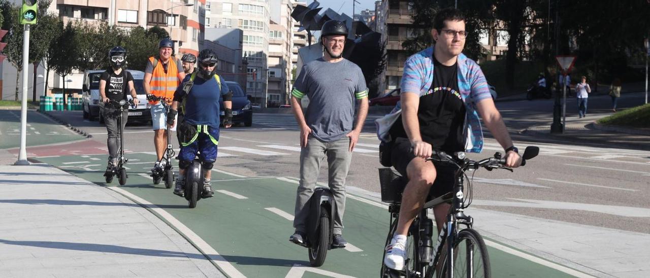 Luis (monociclo), Ánxel (bicicleta) y Bernardo (patín) pasean con el resto del grupo en sus medios de transporte habituales. // RICARDO GROBAS