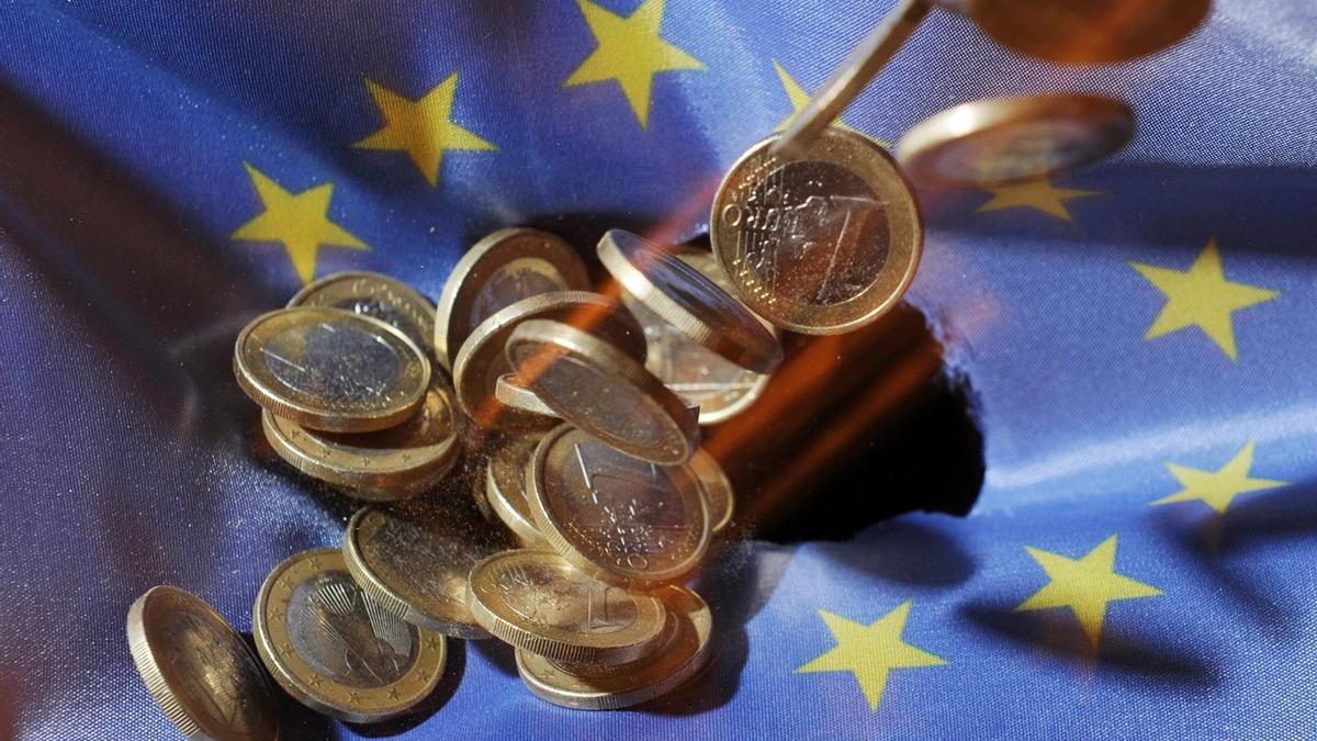 Monedas de euro sobre la bandera de la UE.