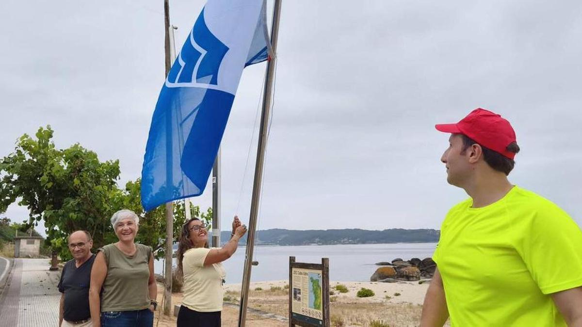 Celso Dopazo, Isabel Quintás y Silvia Carballo izan la bandera azul en Lagos ante la presencia de un socorrista.