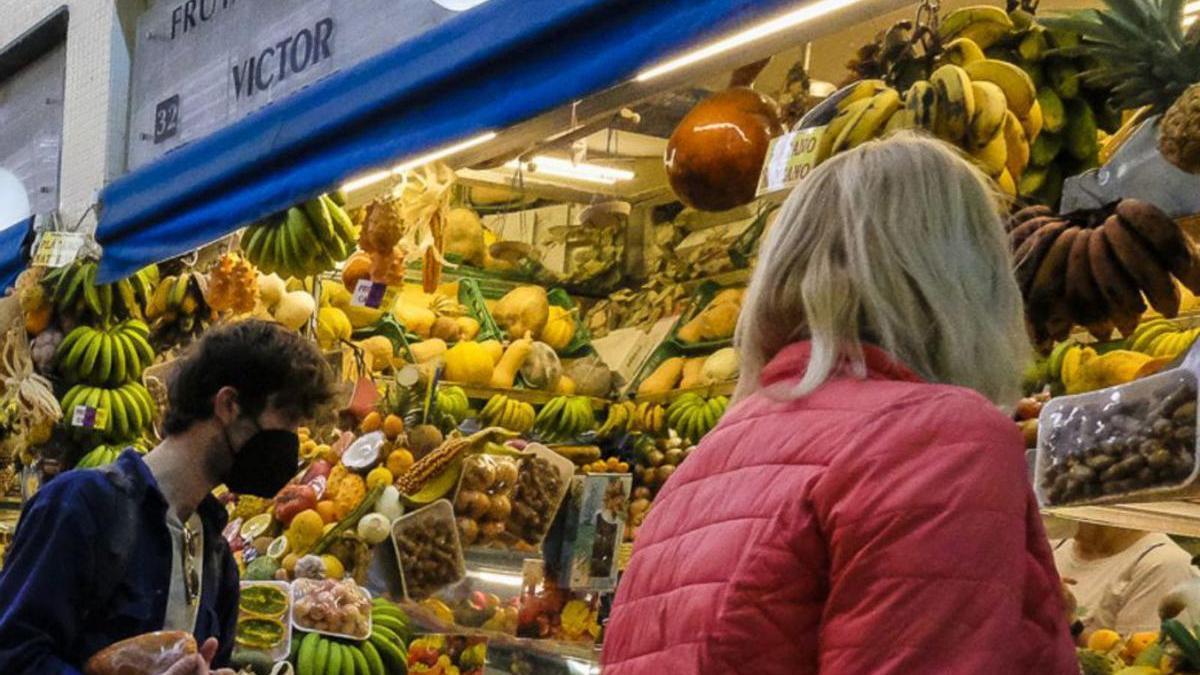 Ciudadanos comparan precios en un puesto de frutas.