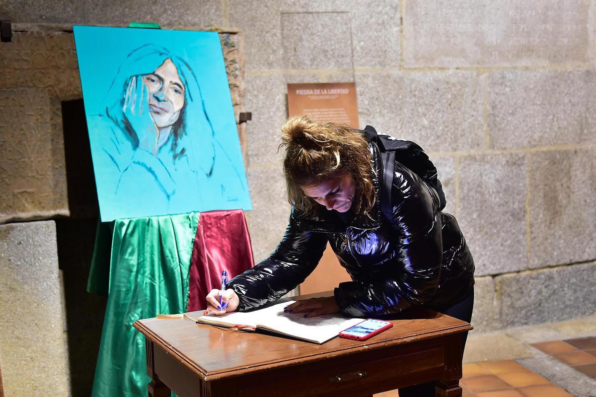 Una mujer escribe en el ibro de condolencias por la muerte de Robe.