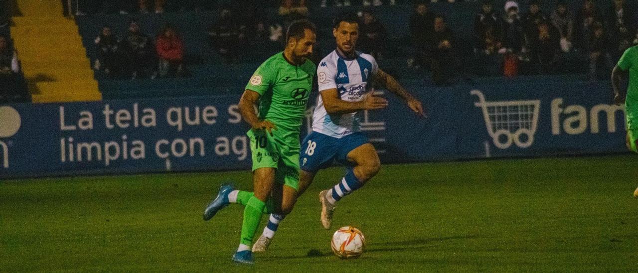 Canario conduce el balón perseguido por Carbonell.