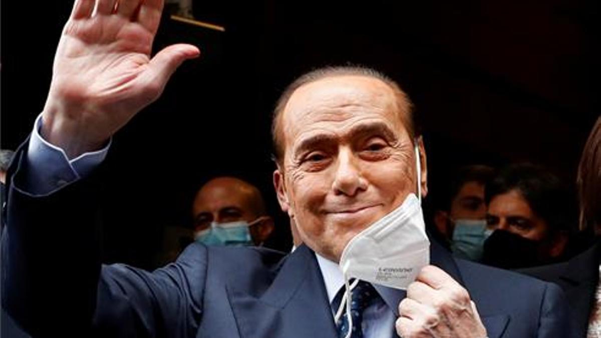 El ex primer ministro italiano Silvio Berlusconi se quita la mascarilla y saluda a su llegada al Palacio de Montecitorio en febrero para las conversaciones sobre la formación de un nuevo gobierno.