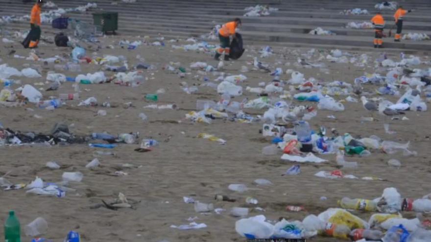 Operarios recogen basura en la playa de Poniente.
