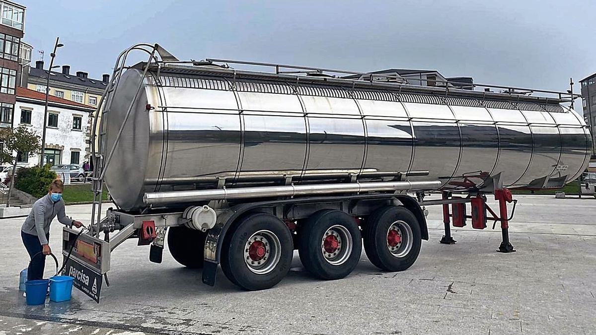 Una vecina, ayer, recoge agua potable de la cisterna en la plaza del Concello en Teixeiro. |   // L.O.