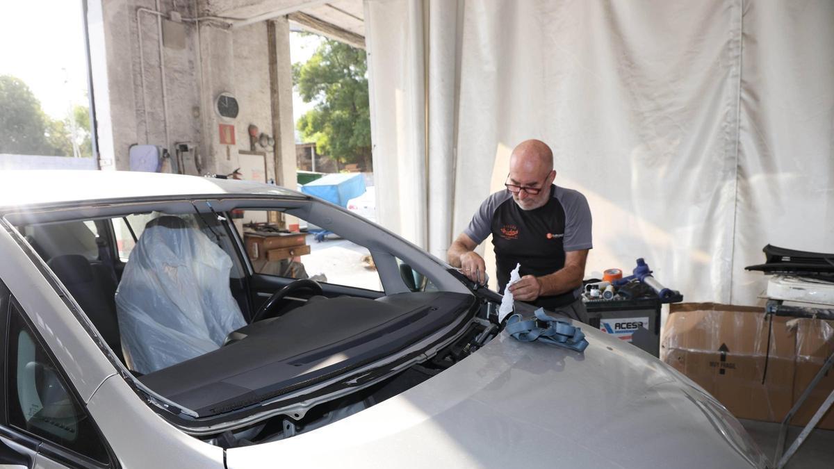 Un trabajador del Taller Unidad, en Vigo, con un coche en reparación.