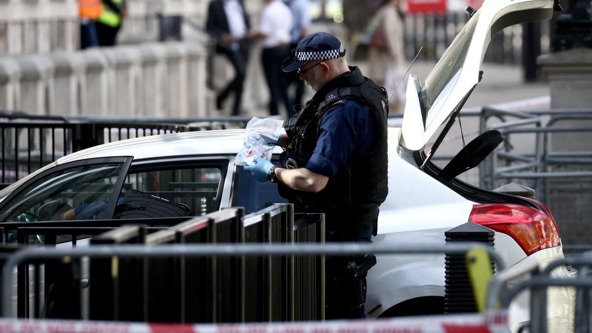 Un policía inspecciona el coche que se estrelló contra la verja del complejo gubernamental de Downing Street, en Londres.