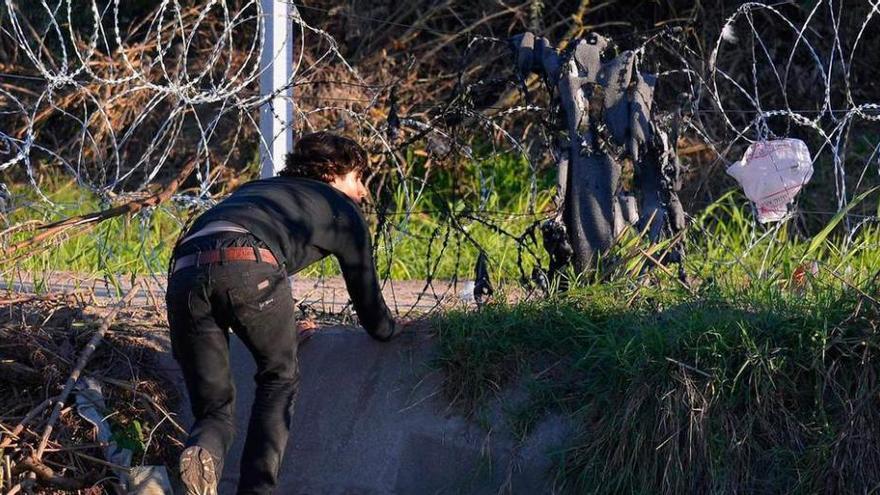 Un joven refugiado atraviesa la valla de espino y cuchillas levantada por Hungría en su frontera con Serbia, a la altura de Röszke.