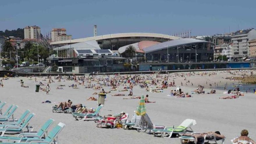 Gente tomando el sol en la playa de Riazor un día de buen tiempo.