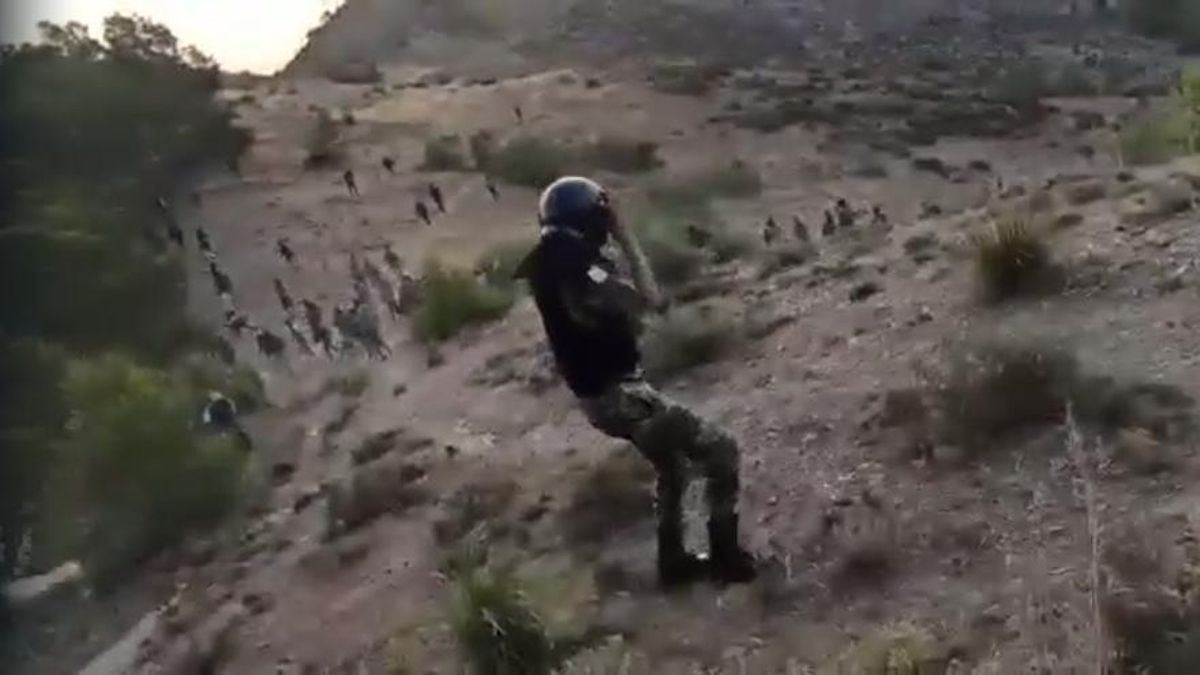 Un gendarme del dispositivo marroquí de disolución de campamentos en el monte Gurugú de Nador, el 22 de junio de 2022. Al fondo, los migrantes que les hacen frente a pedradas.