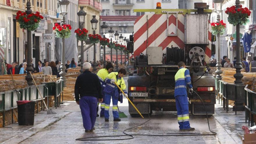 Operarios limpiando la calle Larios tras el paso de las procesiones.