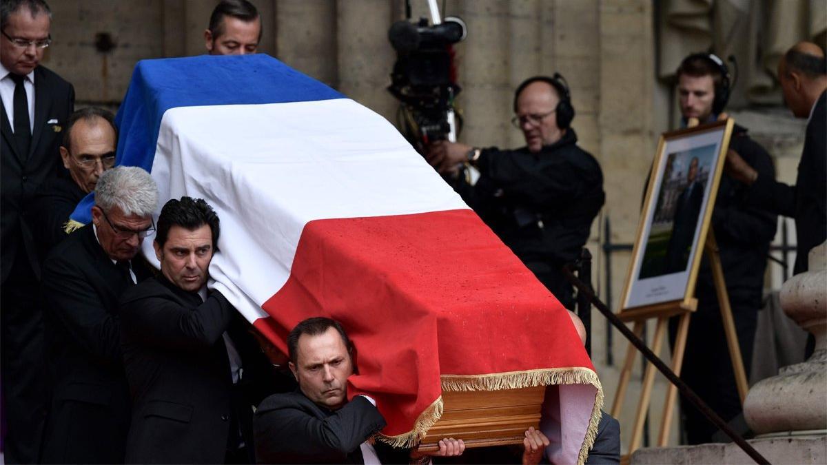 El ataúd del expresidente francés Jacques Chirac, cubierto con la bandera nacional francesa, es llevado por portadores a la salida de la iglesia de Saint-Sulpice, en París, este lunes.