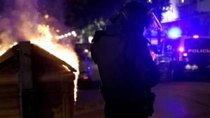 Un policía antidisturbios, junto a un contenedor de basura incenciado en Burgos.