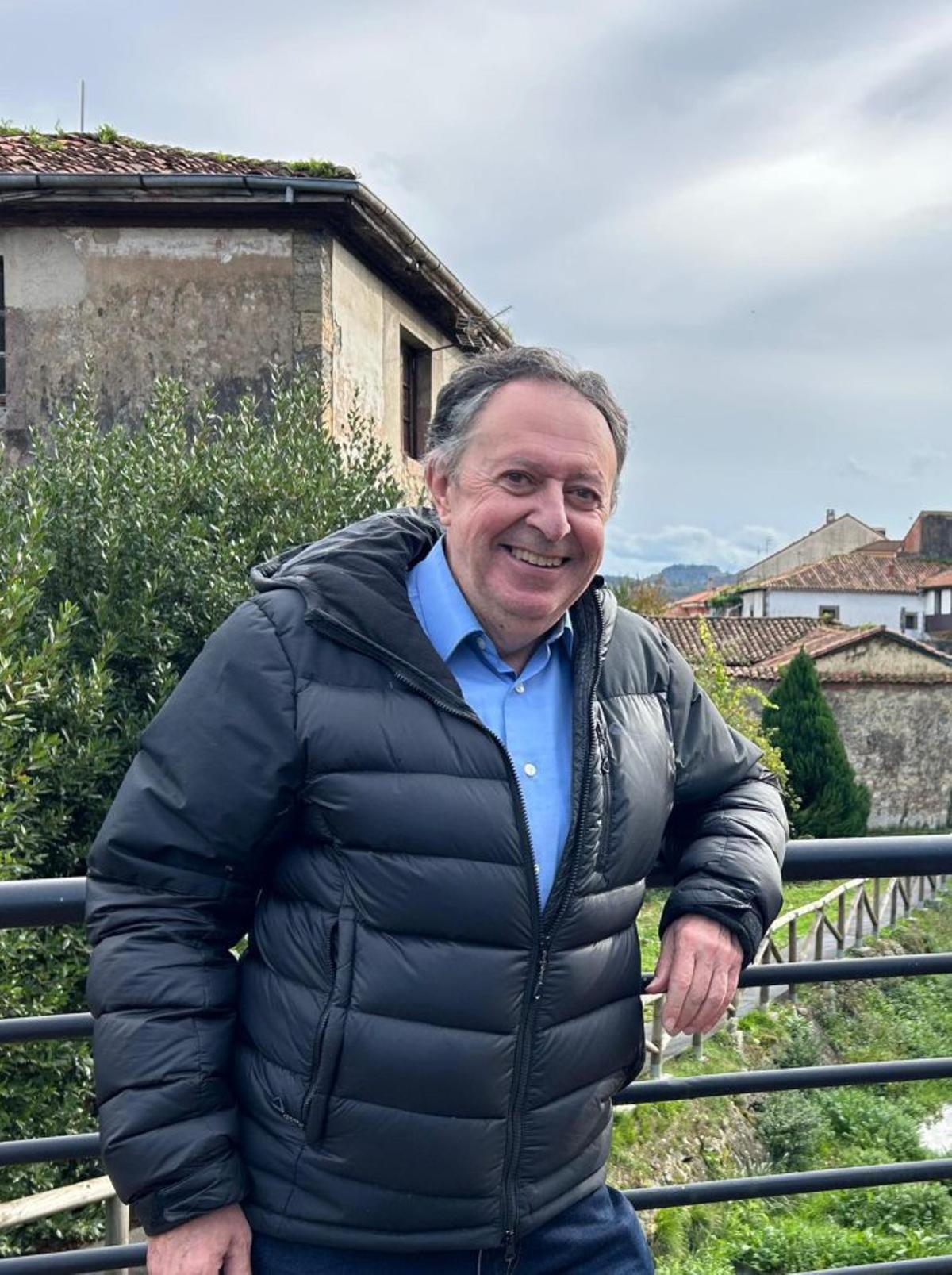 Narciso Larrinaga, vasco residente en Salas, en la pasarela del río Nonaya, con la torre de Valdés-Salas al fondo.