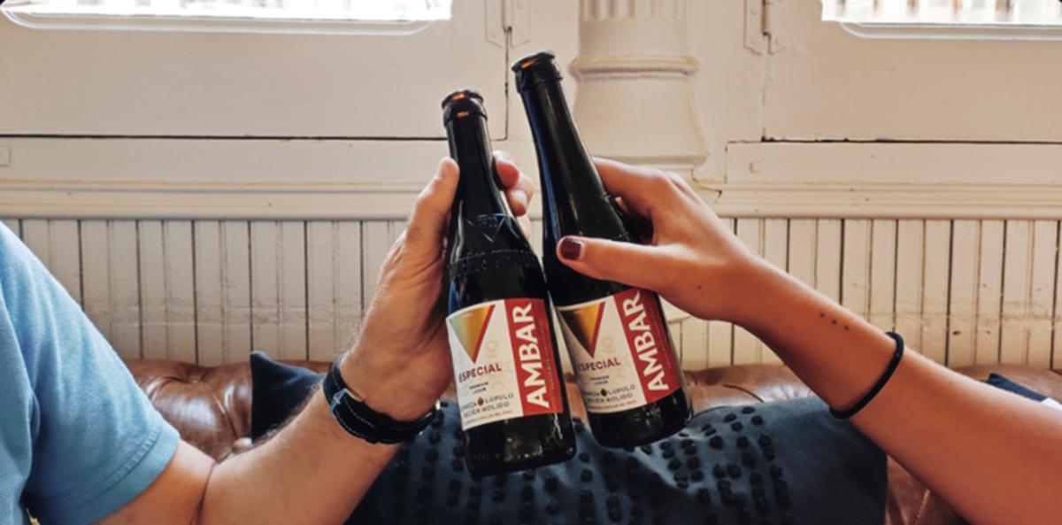 Dos personas brindan con un botellín de Ambar