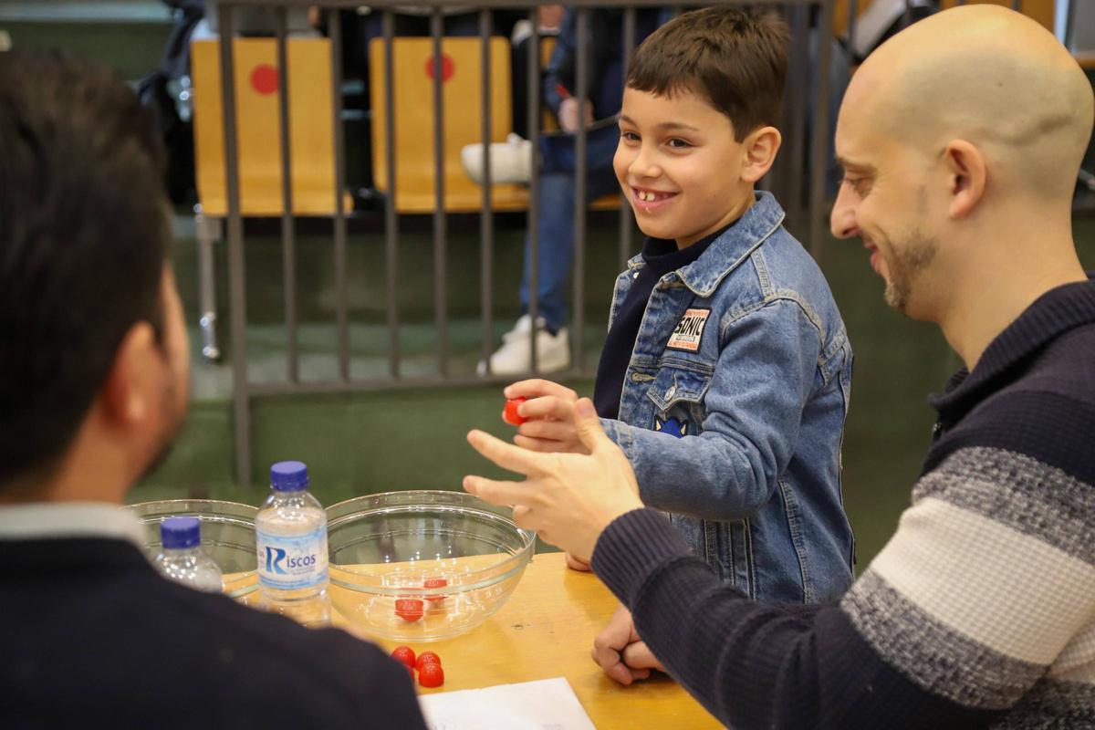 La mano inocente de un niño saca las bolas con los nombres de las agrupaciones.