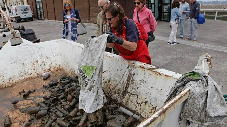 Paseantes contemplan desperdicios retirados por buzos del fondo del puerto deportivo en 2016.