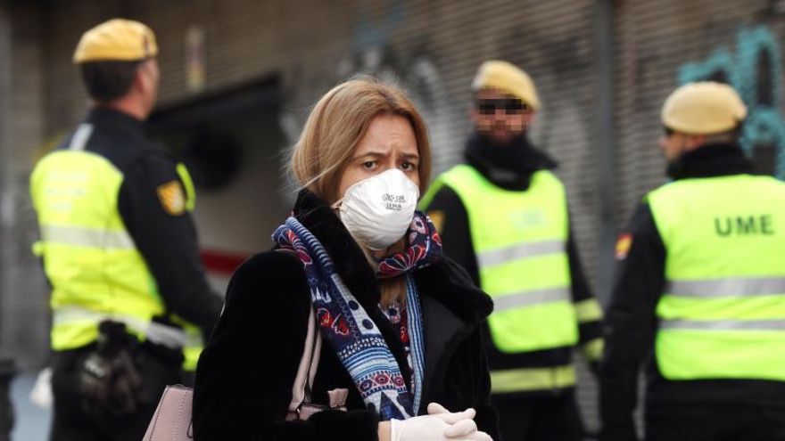 Una mujer camina junto a miembros de la UME en Madrid.