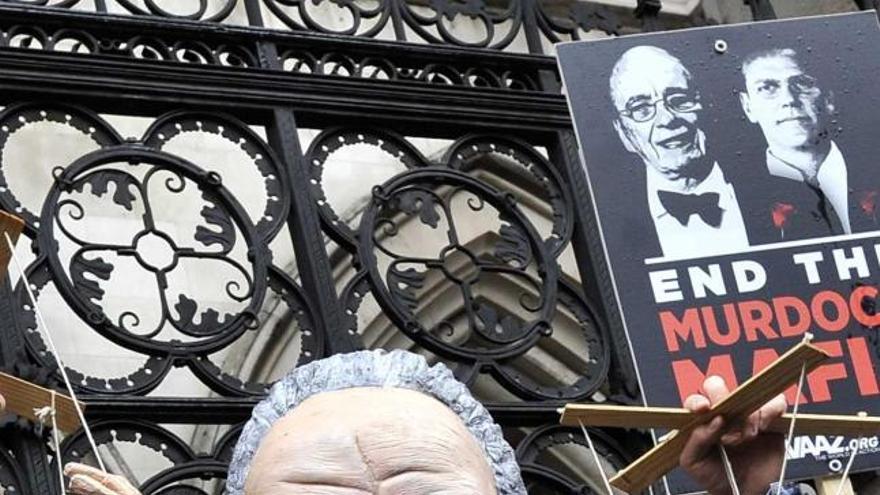 Un manifestante con una máscara de Murdoch sostiene sendas marionetas de Cameron y Hunt.