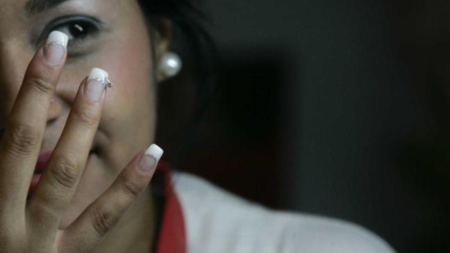 Awi Jáquez, dependienta de un local avilesino especialista en uñas, mostrando sus dedos ( izquierda) y trabajando con una de sus clientas.