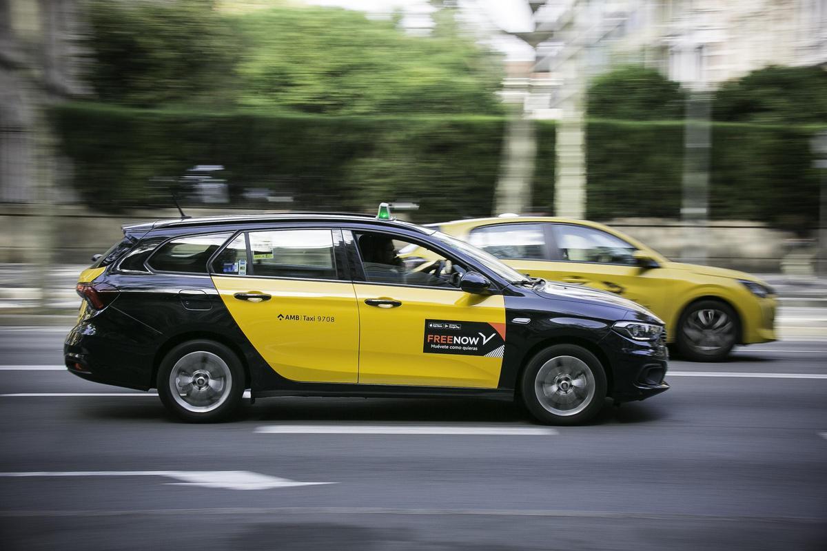 Un taxi con pegatinas de Free Now circula por las calles de Barcelona