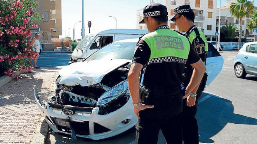 Dos agentes de la Policía Local de Santa Pola ante el vehículo siniestrado ayer.