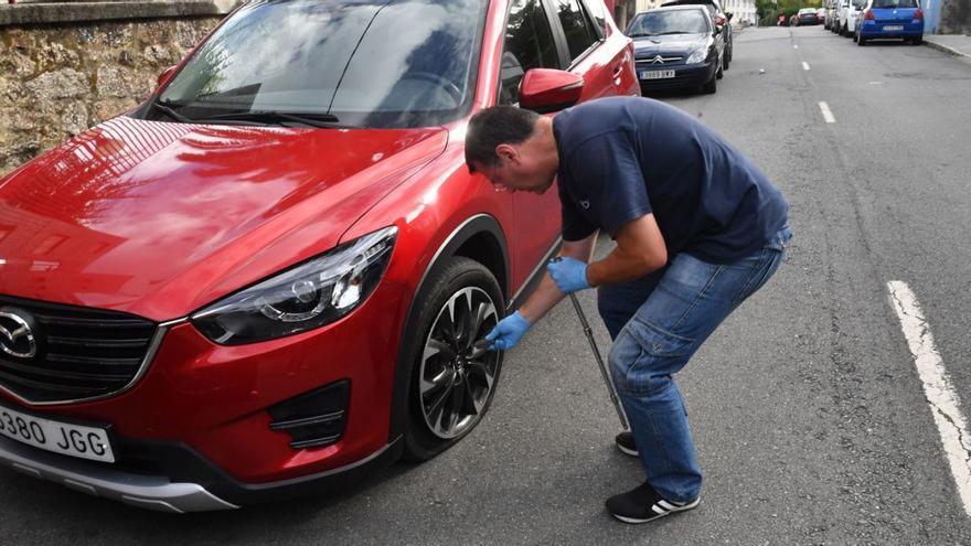 Un hombre cambia la rueda pinchada de un vehículo estacionado en Santa Gema.   | // VÍCTOR ECHAVE