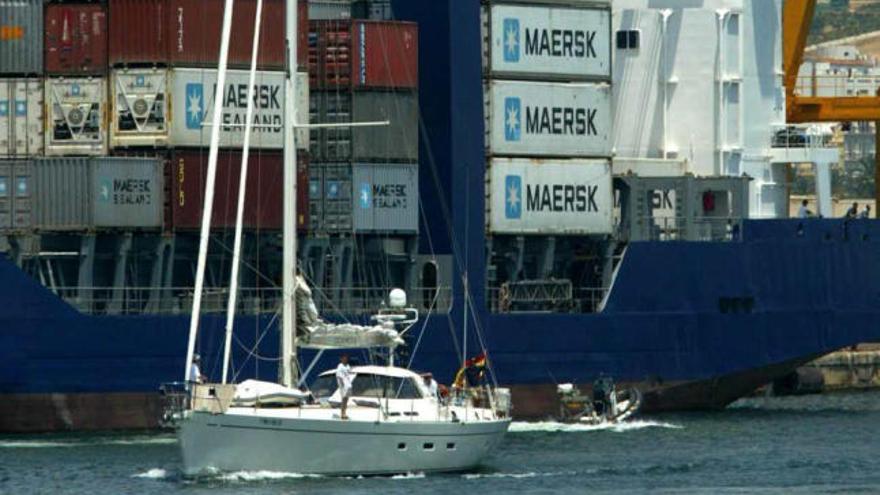 Un embarcación deportiva pasa junto a un barco cargado de contenedores en el Puerto.