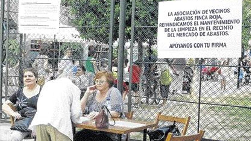 Pancarta colgada en Abastos y mesa de recogida de firmas.