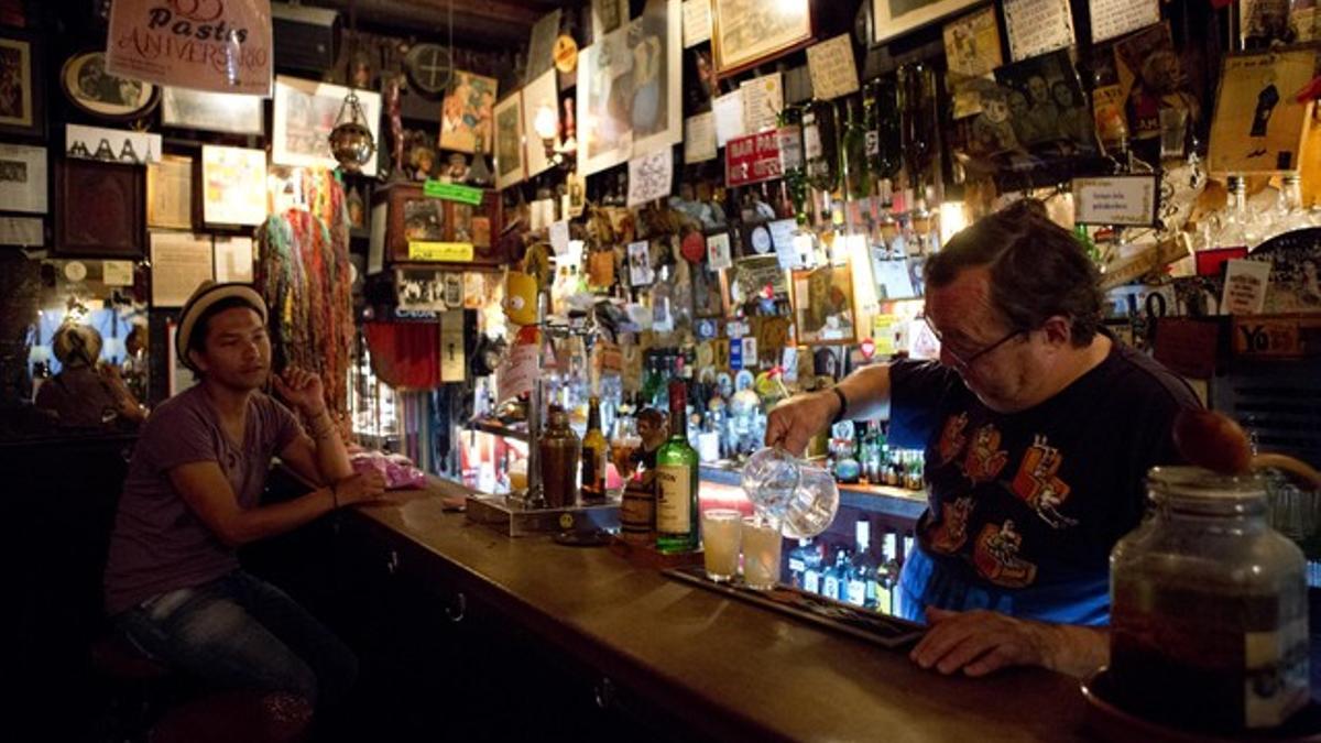 El barman del Pastís, tras la abigarradísima barra del emblemático local.