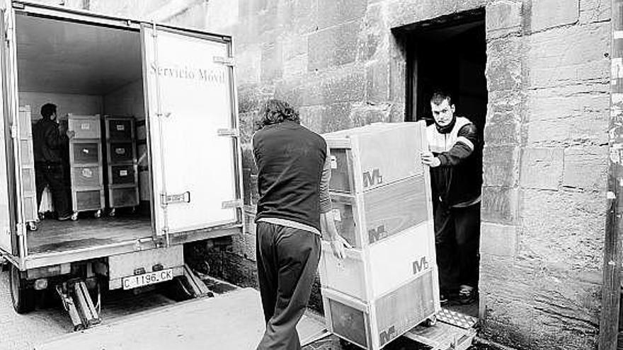 Dos trabajadores cargan las cajas en el monasterio de San Pelayo, sede actual del Archivo Histórico.