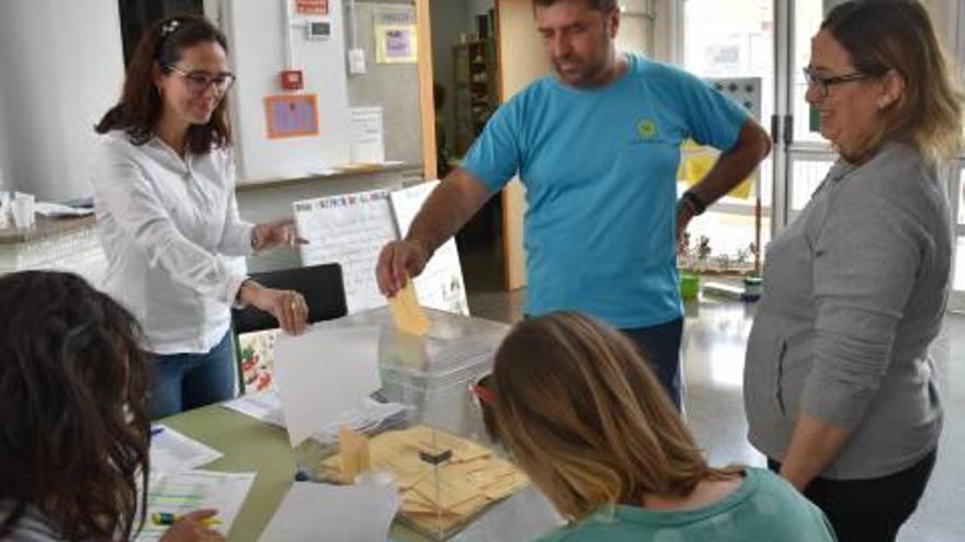 Un padre entrega su papeleta en la votación del colegio Bosch Marín de Carlet.