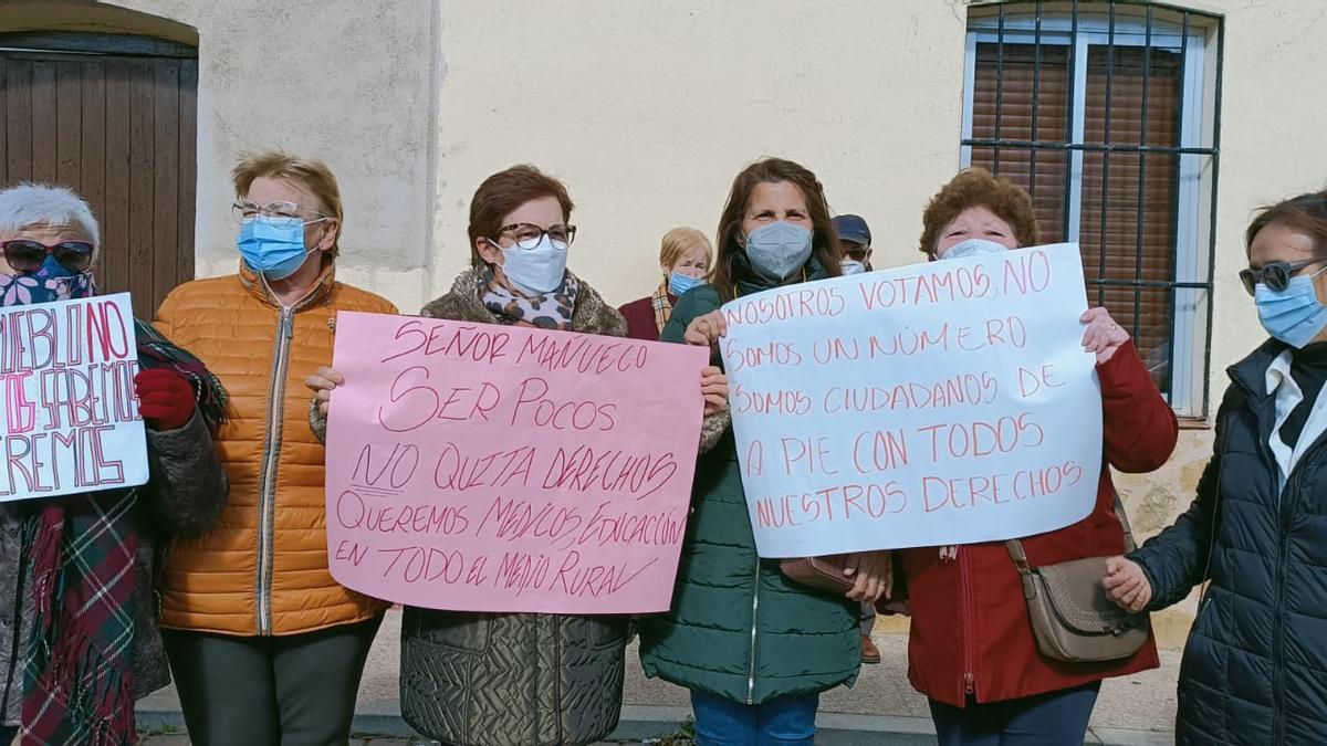 Varias mujeres sostienen pancartas de protesta elaboradas en sus casas.
