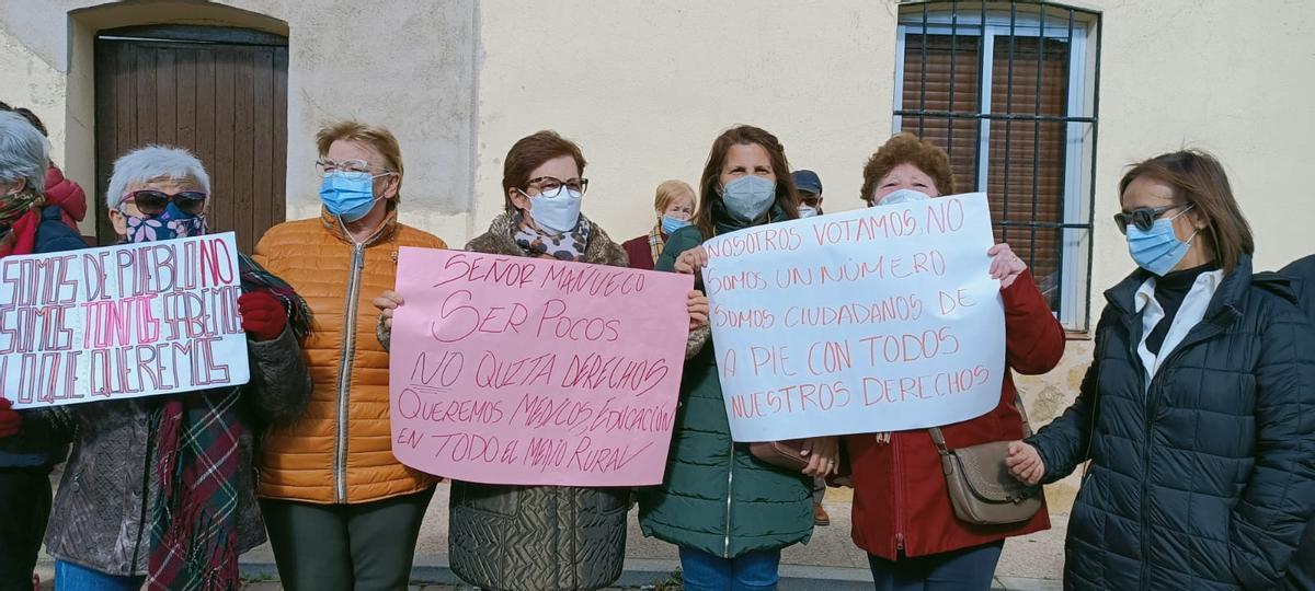 Varias mujeres sostienen pancartas de protesta elaboradas en sus casas.