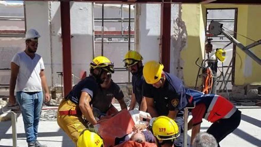 Bomberos y sanitarios trasladan al obrero herido.