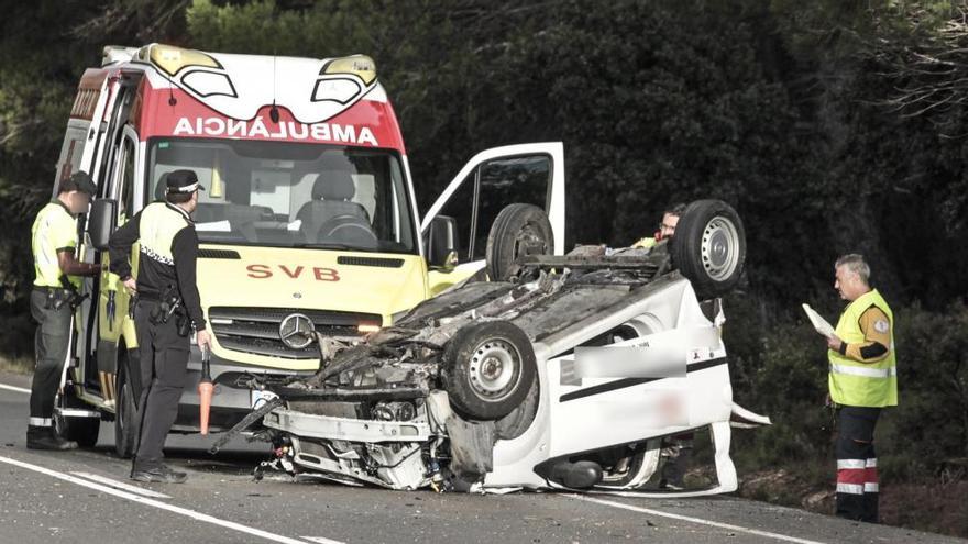 Una ambulancia junto al coche que ha quedado volcado en mitad de la calzada