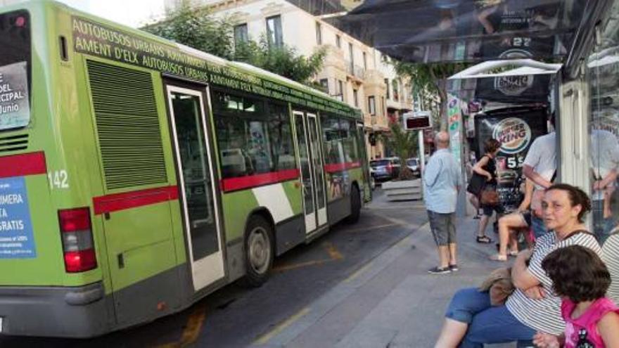 Varios usuarios esperando ayer por la tarde el autobús urbano en la parada situada en la Plaça de Baix.