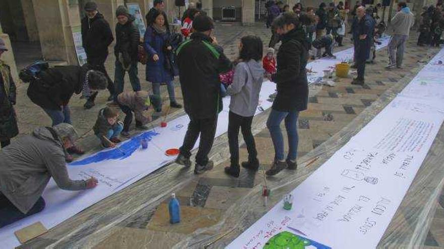 Varios de los asistentes pintando en el papel durante la acción organizada por Salvem el Molinar.