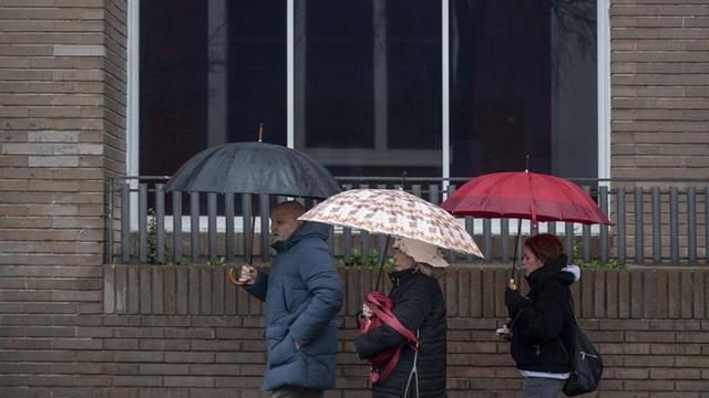 Tres persones es protegeixen amb paraigua de la pluja caiguda a finals de gener