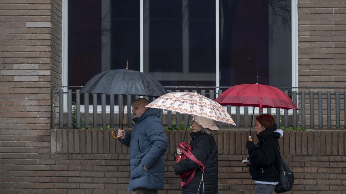 Tres persones es protegeixen amb paraigua de la pluja caiguda a finals de gener a Barcelona.