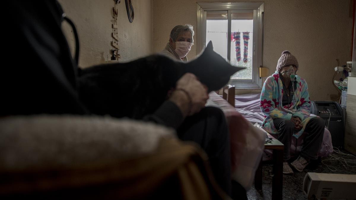 Barcelona    09 01 2021   Barcelona    La senora Carmen sentada en una esquina de la cama conectada al respirador acompanada por su hermana Teresa y su hijo Jose en su casa en el barrio de Torre Baro  Denuncia que el barrio vive con cortes de luz permanentes y sufre por si se va la corriente durante uno de sus tratamientos de dialisis    Fotografia de Jordi Cotrina