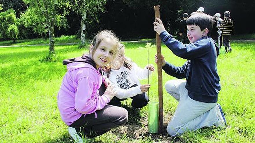 Por la izquierda, Lorena González, Carmen López y Alejandro Díez, ayer, en Navia, plantando un árbol.