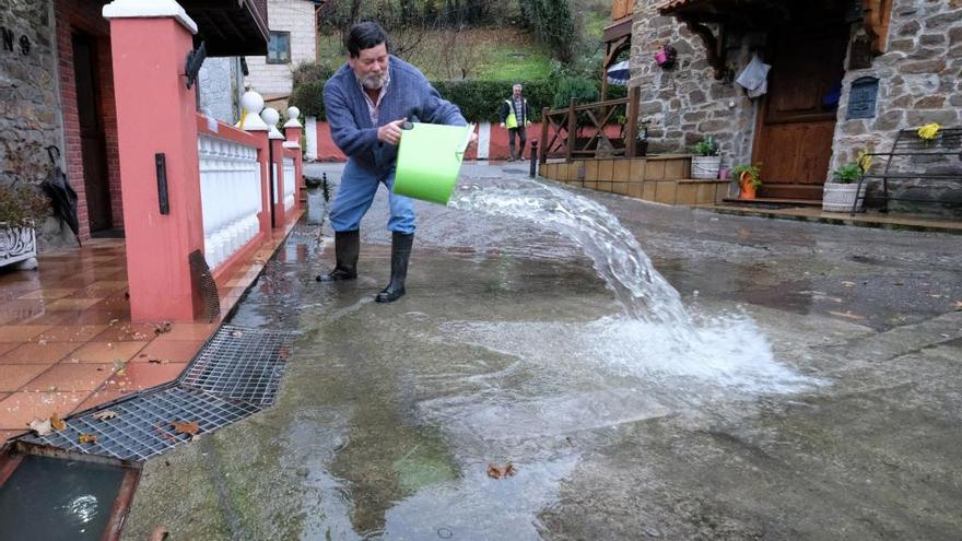 Un vecino de Baiña retira agua delante de su casa.