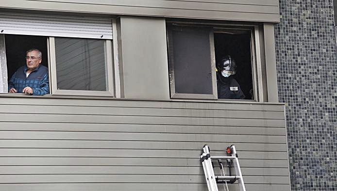 Un vecino se asoma en la ventana de al lado del piso del incendio.| Ángel González