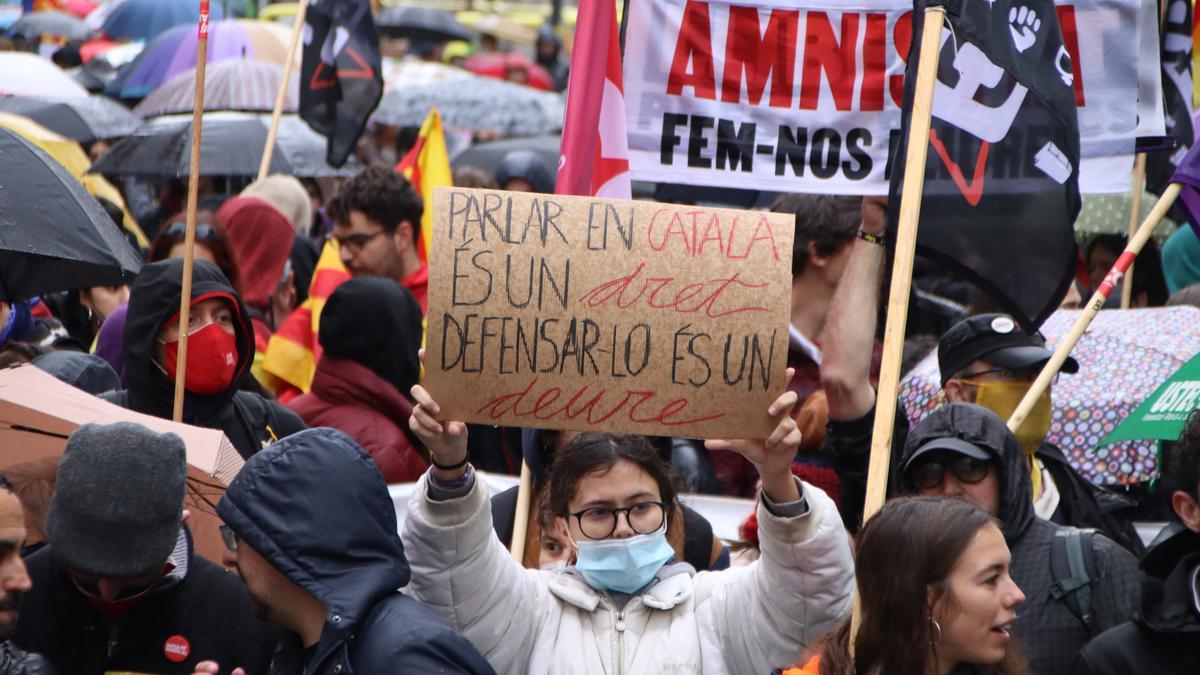 Una manifestant mostra una pancarta en defensà del català durant la manifestació a Barcelona